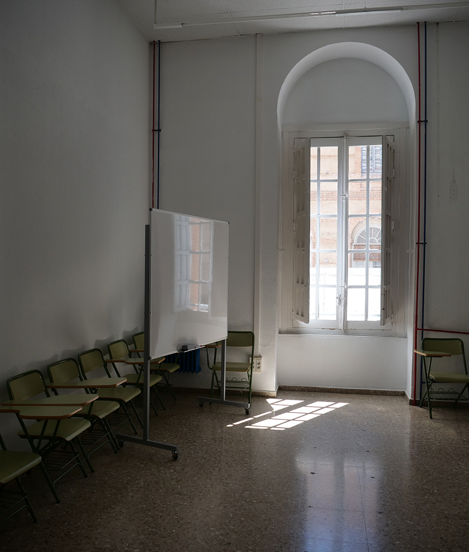 Aula de la Facultad de Comunicación y Documentación con una pizarra, sillas y un ventanal