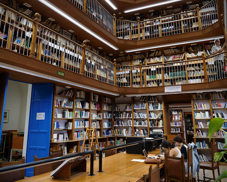Biblioteca de la Facultad de Comunicación y Documentación de cuatro plantas de estanterías con libros y mesas de estudio en la planta baja