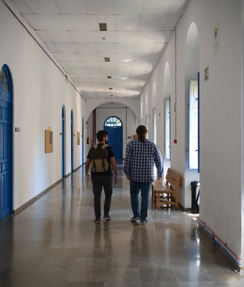 Dos estudiantes caminando por uno de los pasillos de la Facultad de Comunicación y Documentación